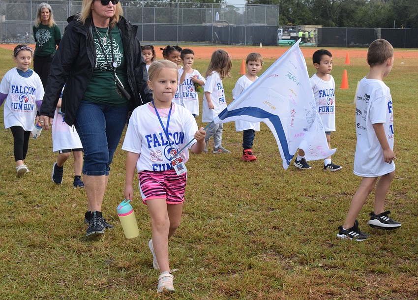 Freedom Elementary School kindergartner Ruby Saxey leads her class onto the field. Each class made a flag to represent their class.