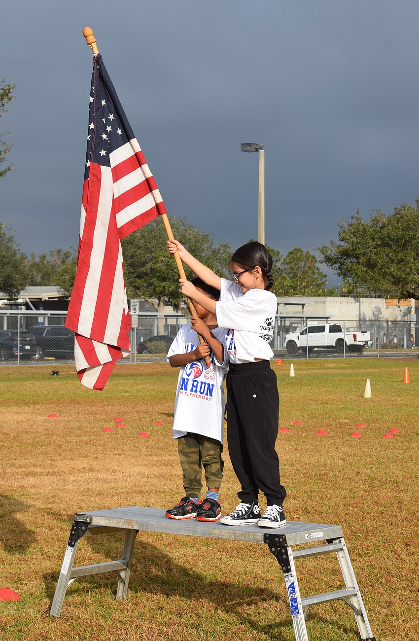Freedom Elementary School first grader Kenia Mata holds the American flag during the national anthem.