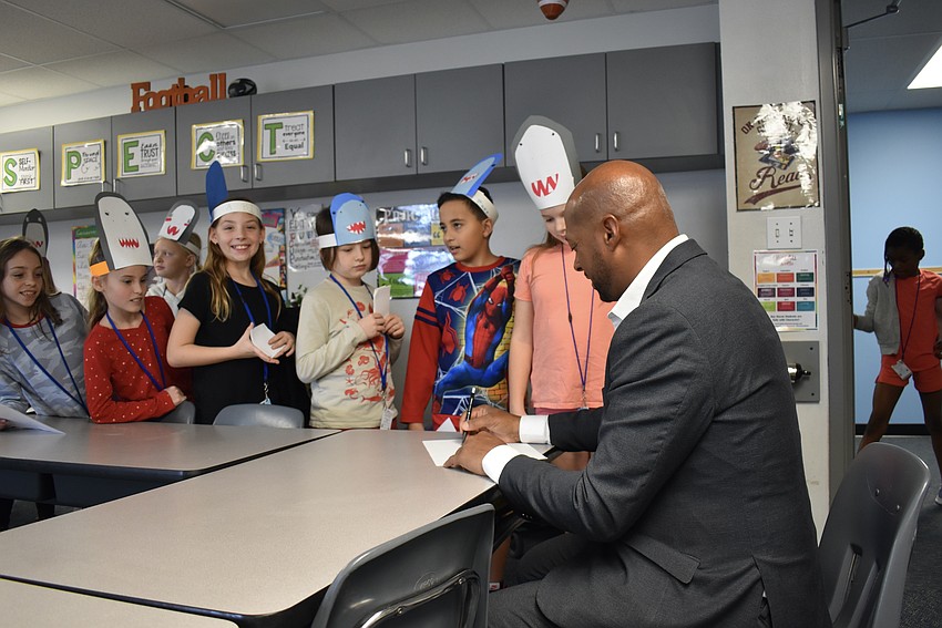 Mayor Kyle Battie signs the students' shark hats.