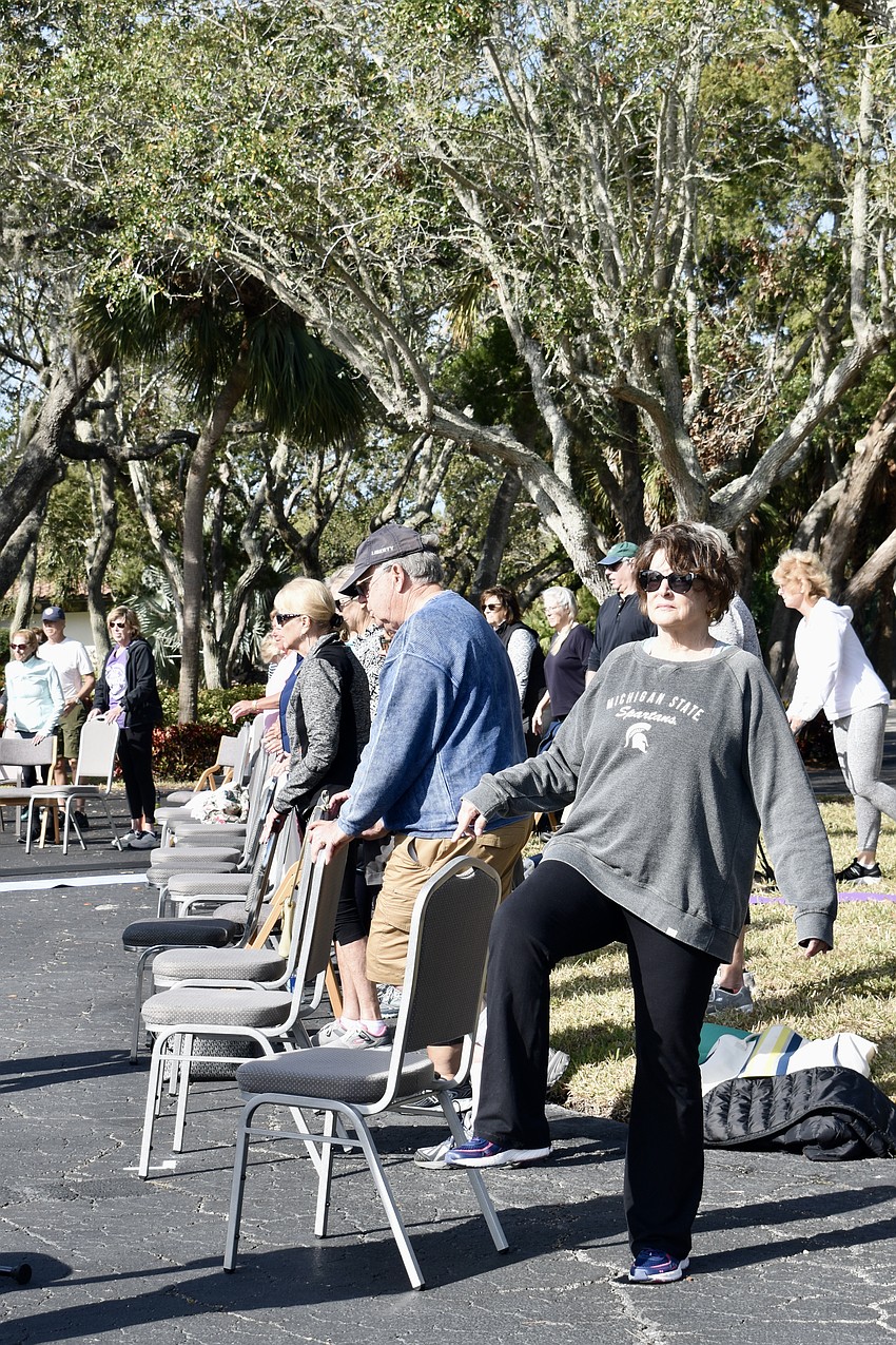 Pam Elder uses a chair to balance during a modified pilates class.