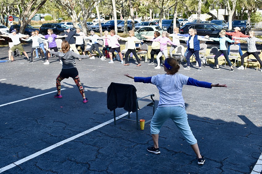 Debby Debile leads and Suzy Brenner follows along during a yoga class.