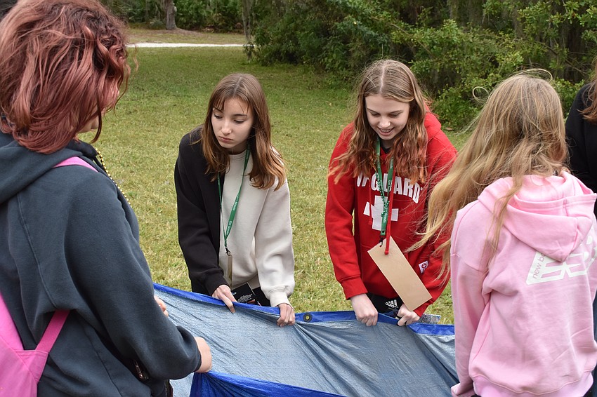 Creekwood 15-year-old Isabella Oliveira, 14-year-old Reese Gurski, Lakewood Ranch 15-year-old Alice Barr, and Palmetto 12-year-old Lacy Kimbrell learn how to lift a tarp to assist an injured individual.