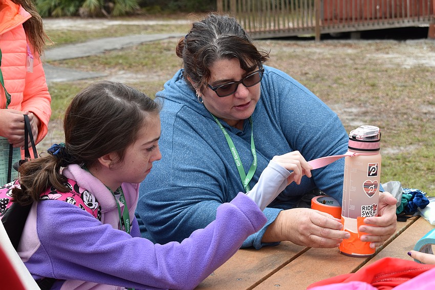 Bradenton 13-year-old Carlee Lesinski learns from Tammy Peters how to make a bottle using duct tape.