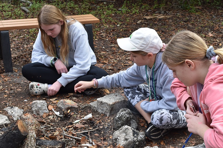 Lakewood Ranch 11-year-old Addison Creel, 12-year-old Keri Evans, and 12-year-old Olivia Drobny try their hands at starting a fire.