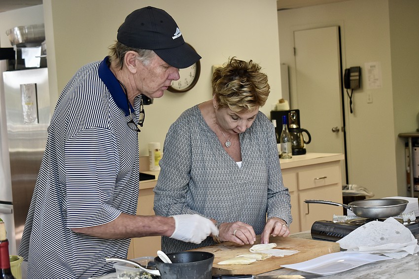 Chef David Stone oversees Karen Pashkow as she folds the spanakopita.