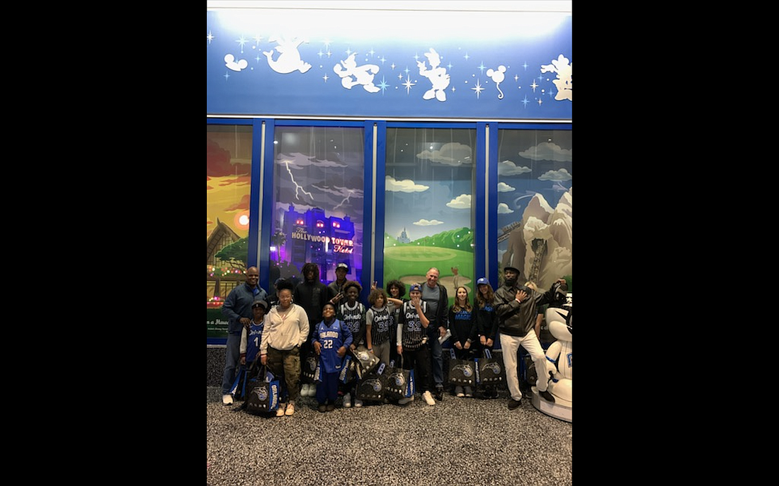 Ormond Beach Police Officer Greg Stokes (far left), developer Paul Holub (middle) and the students he brought to the Orlando Magic game. Courtesy photo