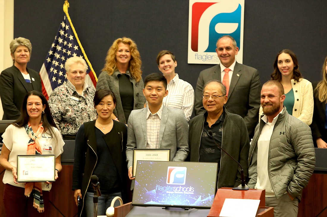 FPC's Brendan Wang, Flagler's Sunshine State Scholar, front center, flanked by his parents, with Heidi Alves, left, FPC Principal Bobby Bossardet, right,  Superintendent Cathy Mittelstadt, top left, and School Board members.