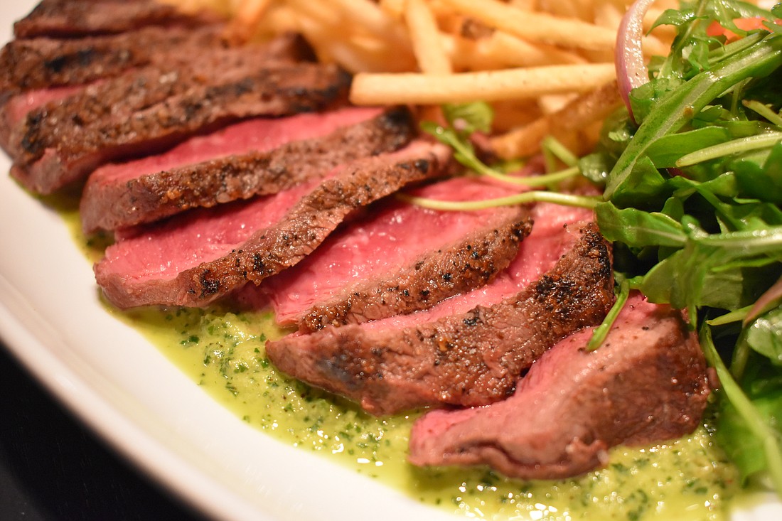 The steak frites features chimichurri Sauce and french fries.