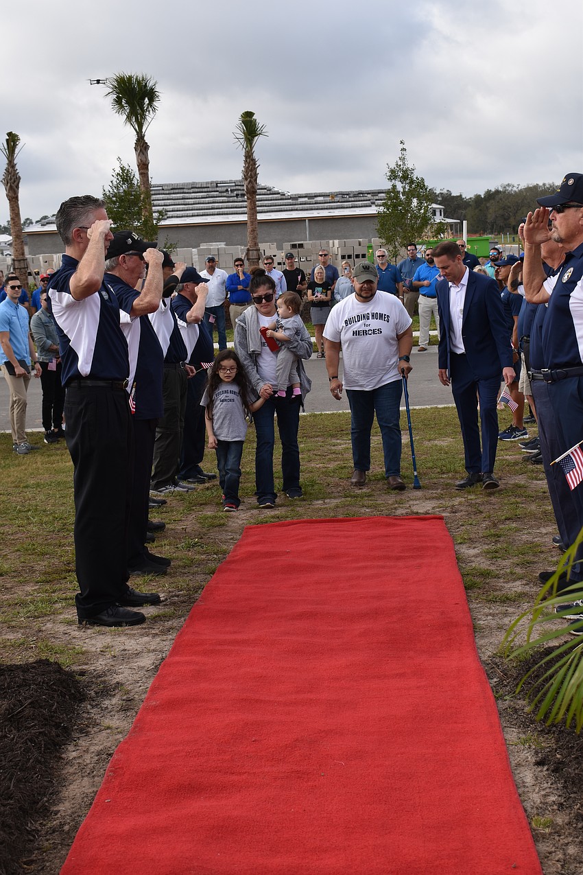 Army Sgt. Lucio Gaytan and his family are saluted as they walk the red carpet to their new home site.
