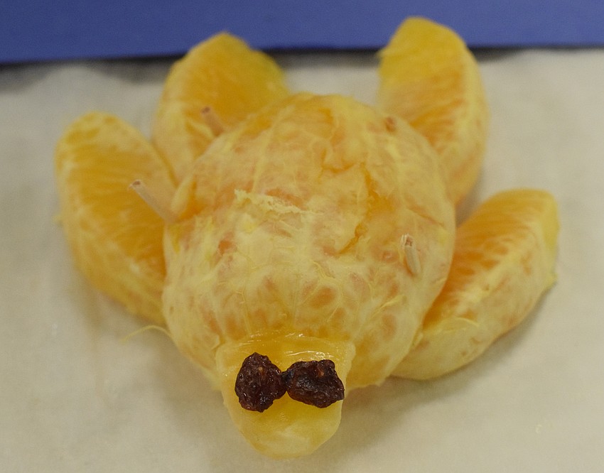 A simple, and yet juicy, sea turtle is made out of orange slices and raisins.
