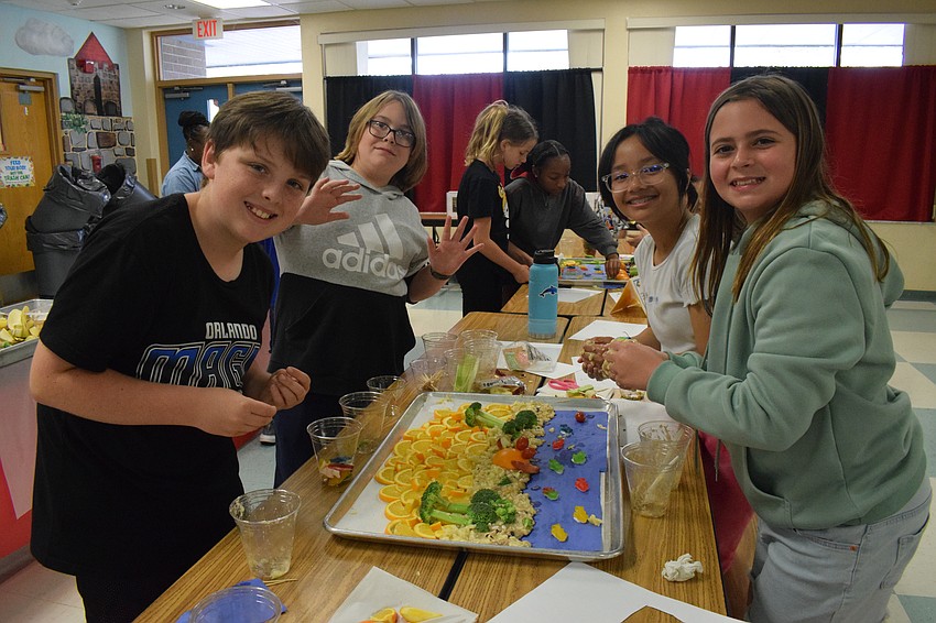 Fifth graders Micah French, RJ Griffis, Kaitlyn Do and Kinley Chupp have no problem getting their hands dirty as they create their Florida sunset using various fruits and vegetables.