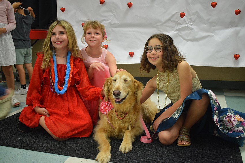 Third graders Mia Sacchi, Jade Servetz and Faxon Schiller have fun petting Callie, the school's therapy dog.