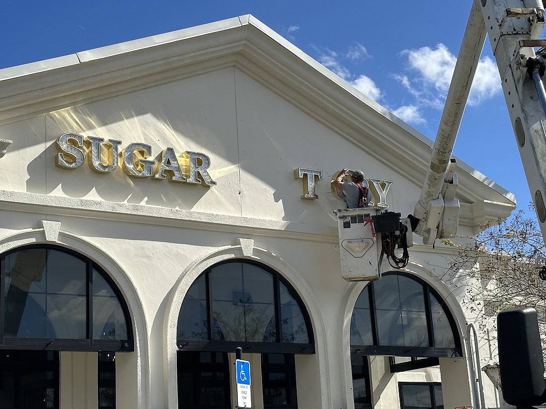 A worker from Taylor Sign & Design Inc. works on installing the sign for Sugar Factory American Brasserie.