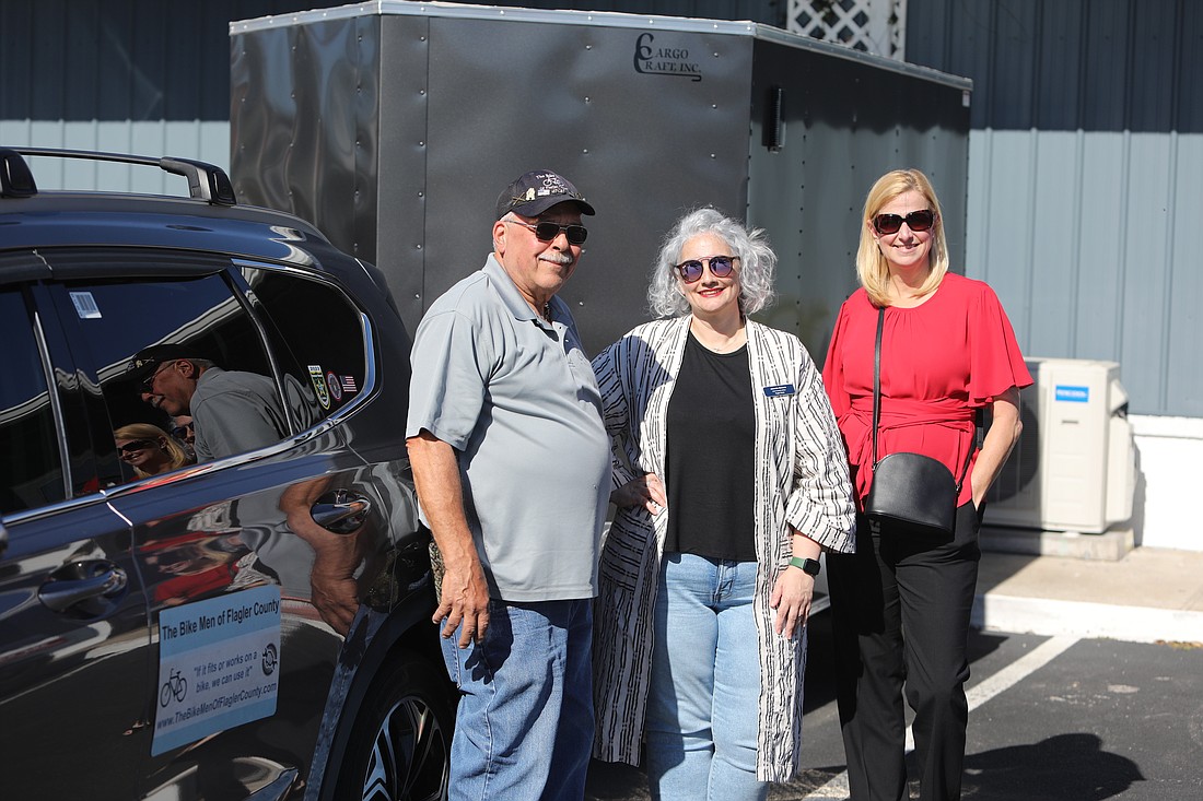 The Bike Man, Joe Golan, stands in front of his new trailer with Flagler Cares' Jeannette Simmons and Carrie Baird. Photo by Brent Woronoff