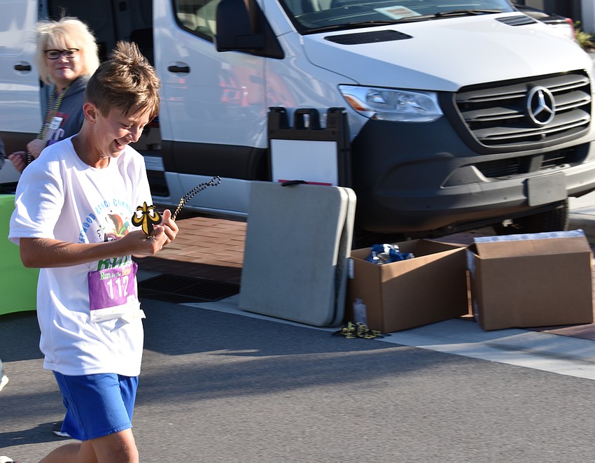 Lakewood Ranch's Mason Brondyke, 11, obviously likes the medal he was handed after finishing the race.