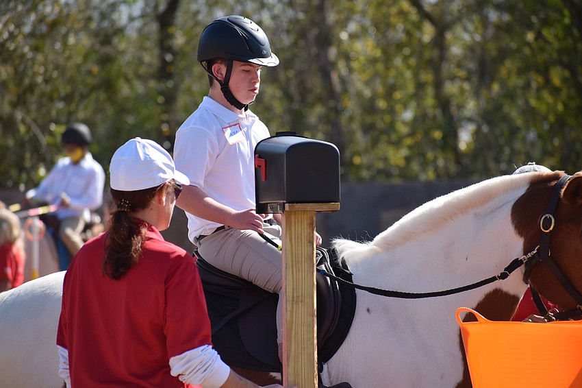 Hooves with Heart volunteer Melissa Newton walks with Lakewood Ranch's 13-year-old Mason Kramer as he approaches the mailbox.
