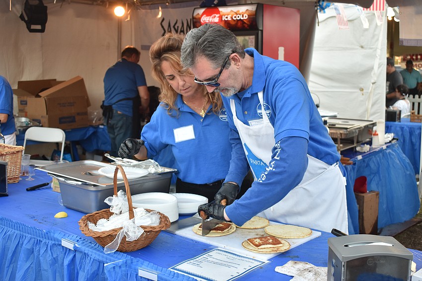 Sarasota's Renee Amoratis and Boca Raton's Tom Coplos slice sagnaki on pita bread.