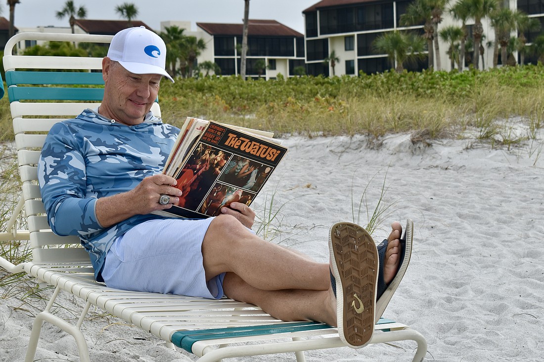 Gary Saunders reads some records on the beach.