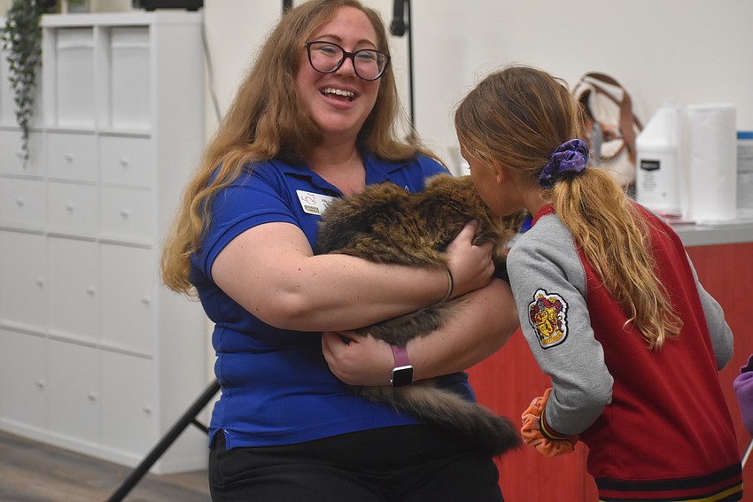 Cat Depot Humane Educator Ellie Levine holds Winney as Olivia Albury kisses his head.
