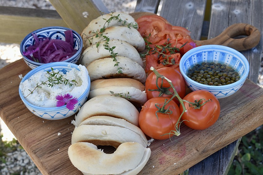 A bagel board with pickled onions, herb cream cheese, tomatoes and capers.