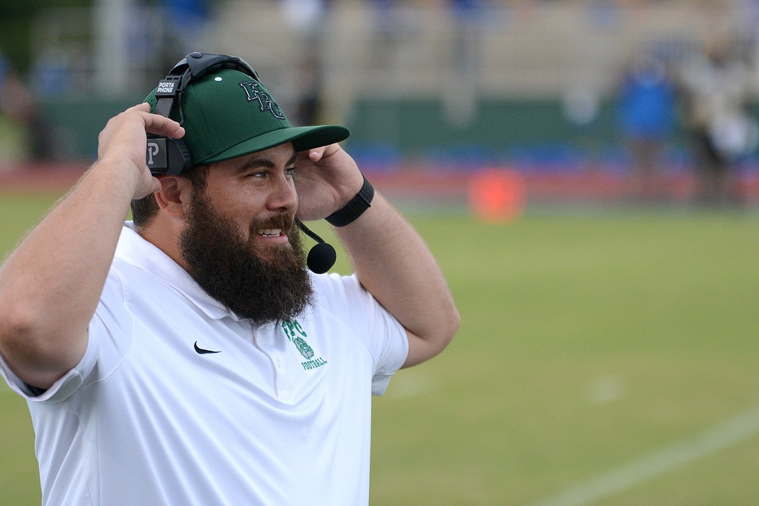 Robert Paxia puts on the headsets for his first game as the head football coach at Flagler Palm Coast on Sept. 3, 2021 at home against Mainland.