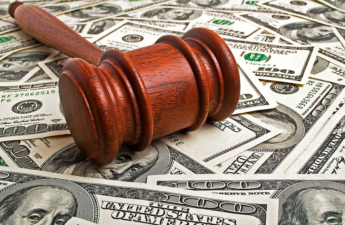 A wooden gavel with American dollars. Photo from Adobe Stock