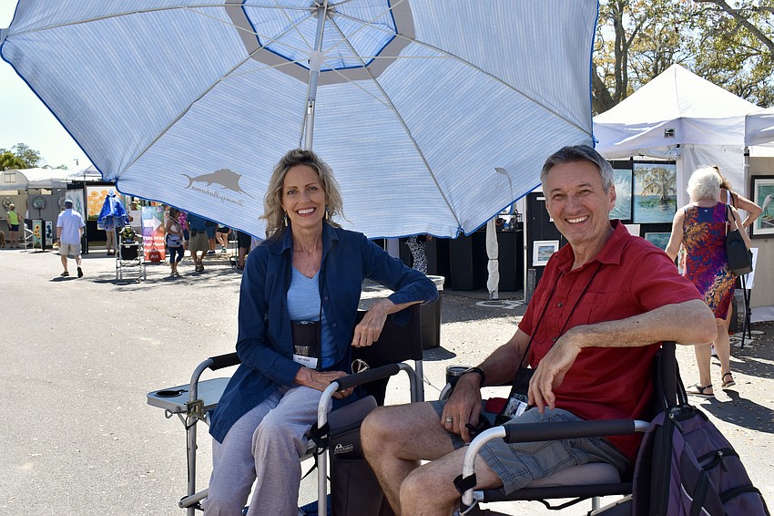 Cat and Simo Tesla sit in the shade by Cat's booth. Cat uses oils and acrylics to paint contemporary, nature-based abstractions.