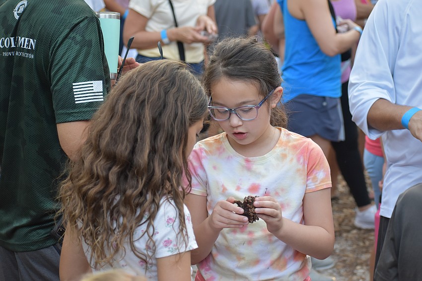 Sarasota 8-year-old Rhea Krolik and Edgewater 8-year-old Emma Ives examine things they found during a Community Campout nature walk.