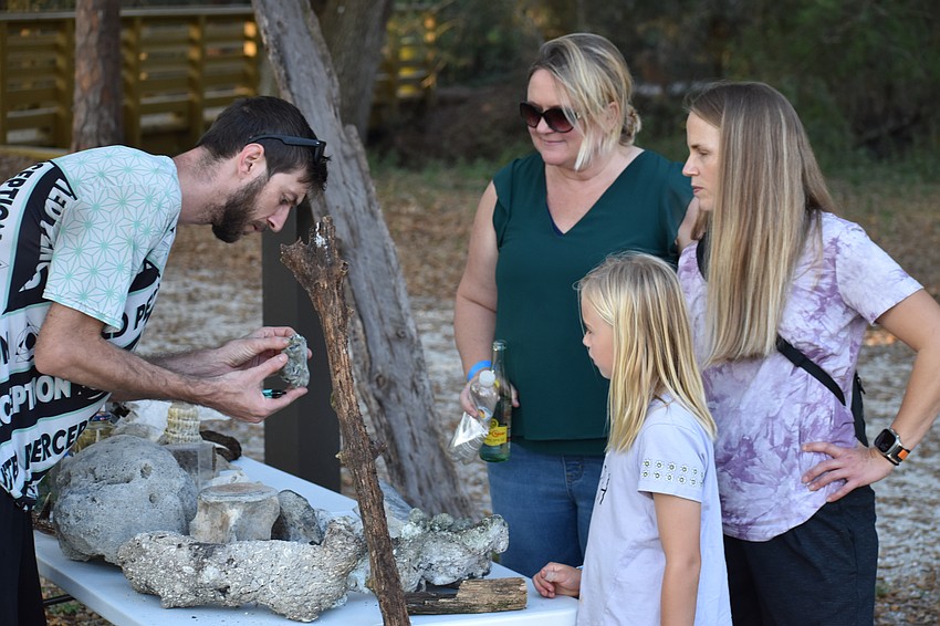 Blake Padgett, Melissa McDermott, 9-year-old Josie Reed, and Lisa Reed examine a collection of fossils and artifacts at the Community Campout.