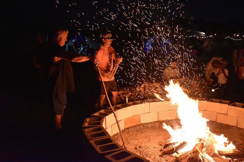 Windsong Acres' Daryl Haworth and Arbor Grande's Michael Bugel stirs the flames at the Community Campout.