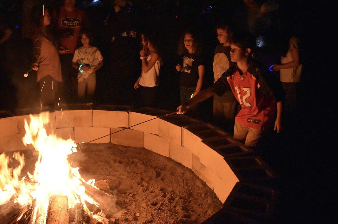 Eleven-year-old Liam Pacheco (No. 12 on his shirt) roasts a marshmallow during the Community Campout.