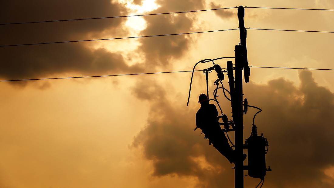 The silhouette of power lineman climbing on an electric pole with a transformer installed. Photo from Adobe Stock