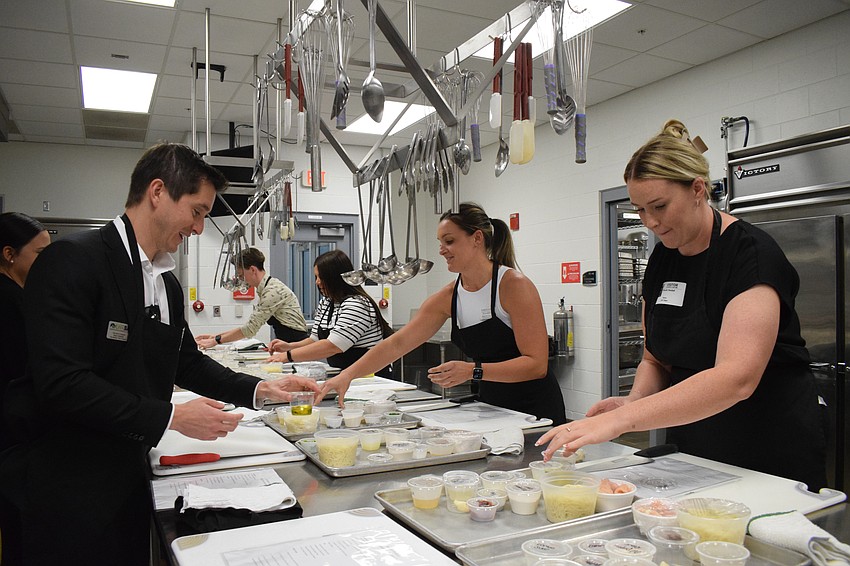 Lakewood Ranch Young Leaders Alliance members Tieler Gittleman, Kristin Caulley and Nicole Hackel receive cooking instructions during a special event at MTC.