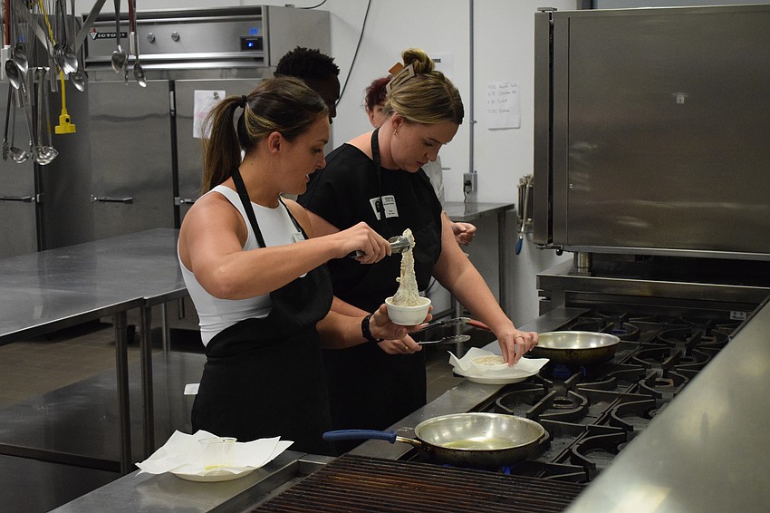 Lakewood Ranch Young Leaders Alliance members Kristin Caulley and Nicole Hackel prepare their chicken for frying.