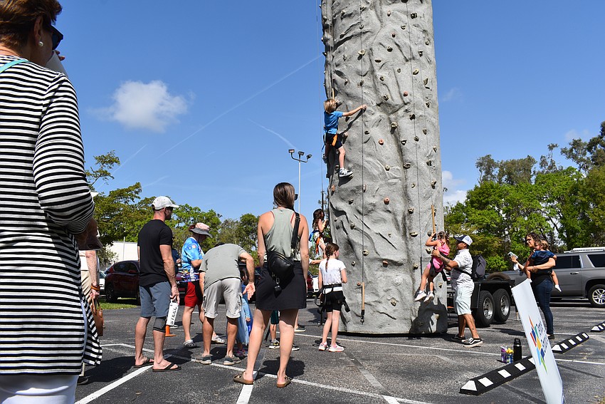 Families watch kids attempt to climb the rock wall at Temple Emanu-El Purim Carnival.