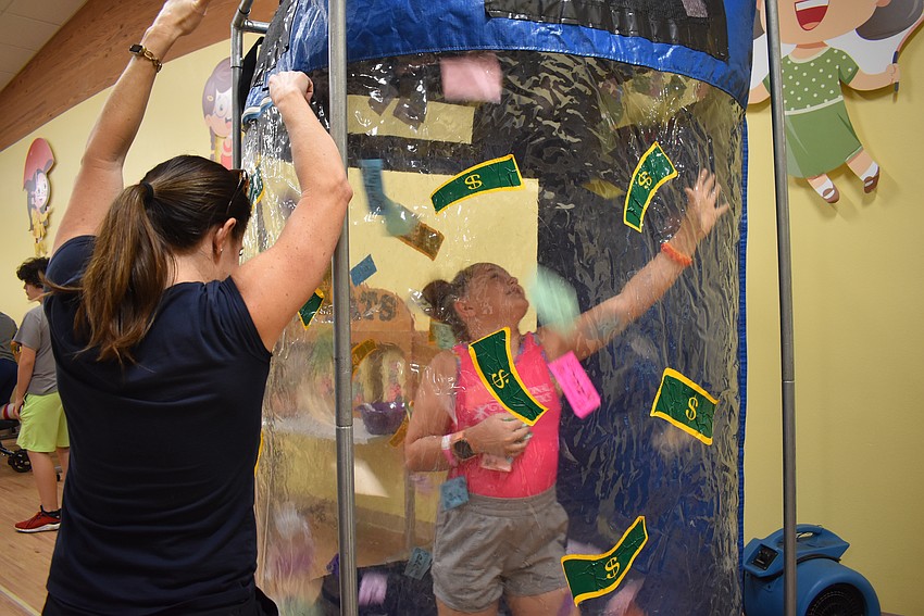 Eloise Friedman jumps in the money machine and grabs as many bills as she can.