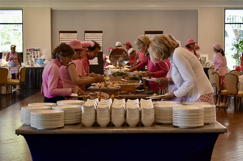 The golfers fill their plates from the buffet.