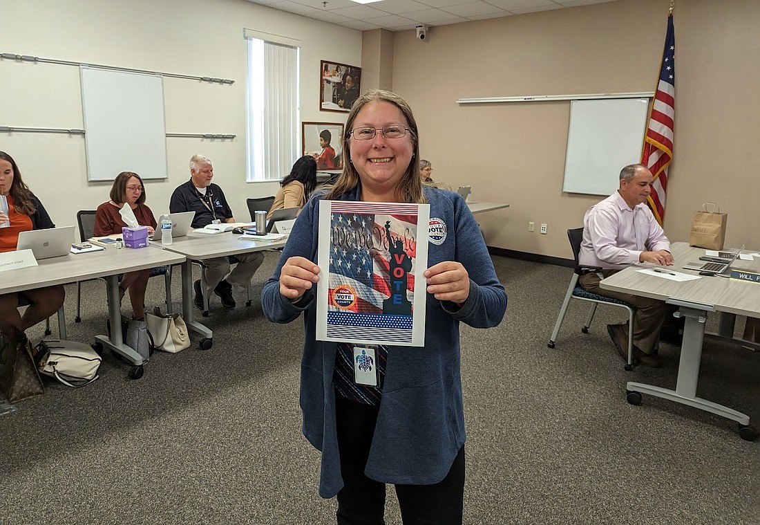 Flagler County Supervisor of Elections Kaiti Lenhart holds up the winning Voter's Guide cover design.
