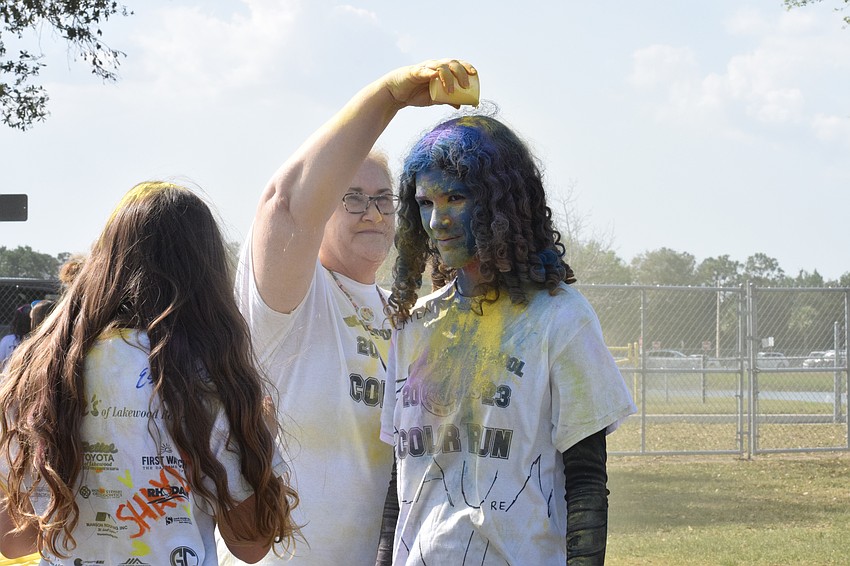 U.S. history teacher Julie Williams pours yellow baby powder over eighth grader Leila Borghesi's head. Borghesi says it was bittersweet to be participating in her last Color Run.