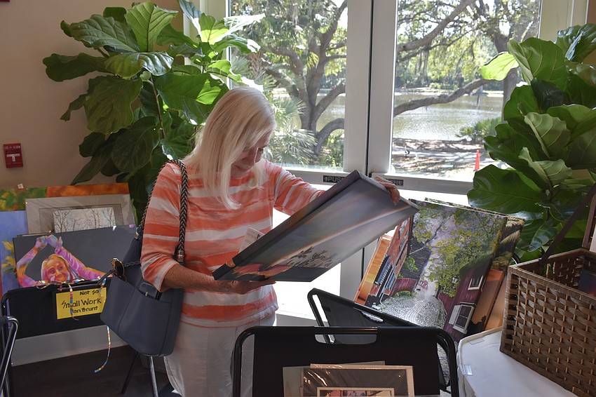 Lakewood Ranch's Pat Wallington examines the artwork for sale.