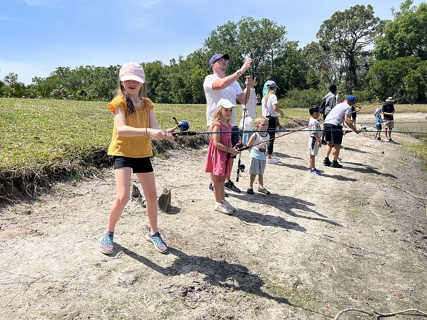 Lorraine Lakes' Aria Lessard, who is 8, learns how to cast for the first time with her 7-year-old sister Alexis Lessard, her father, Chris Lessard, and 5-year-old brother Carson Lessard.