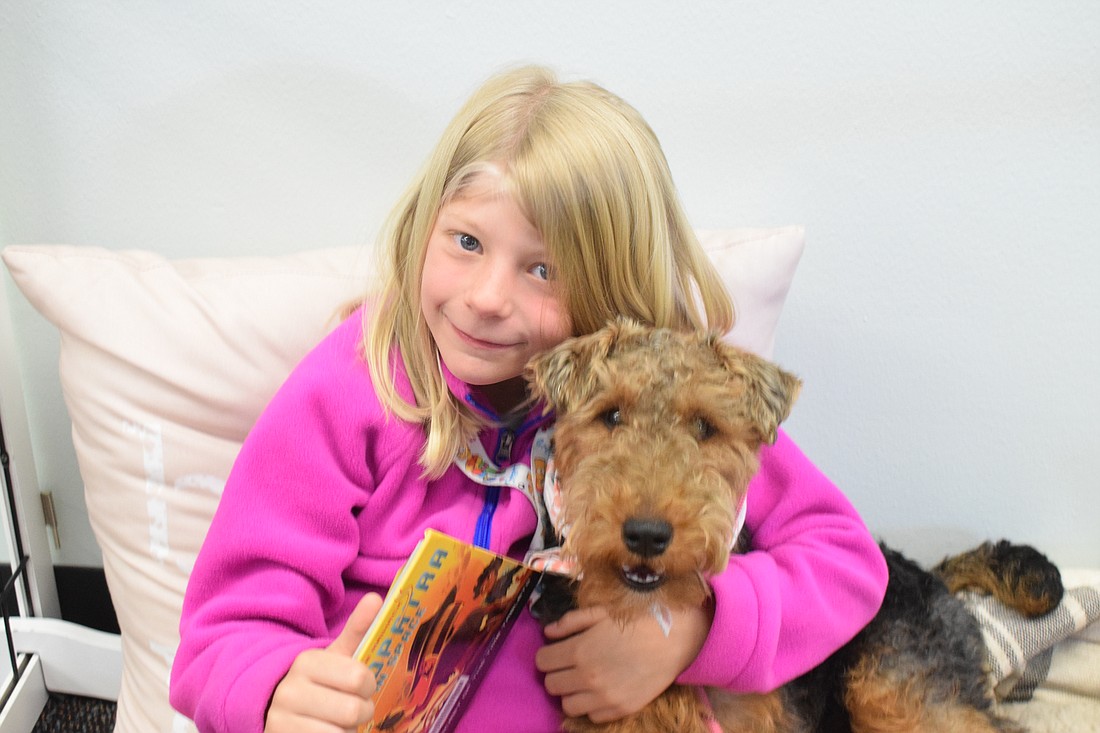 Allison Coleman, a second grader at Myakka City Elementary School, snuggles with Ruby Sue, the school's future therapy dog, while reading to her.