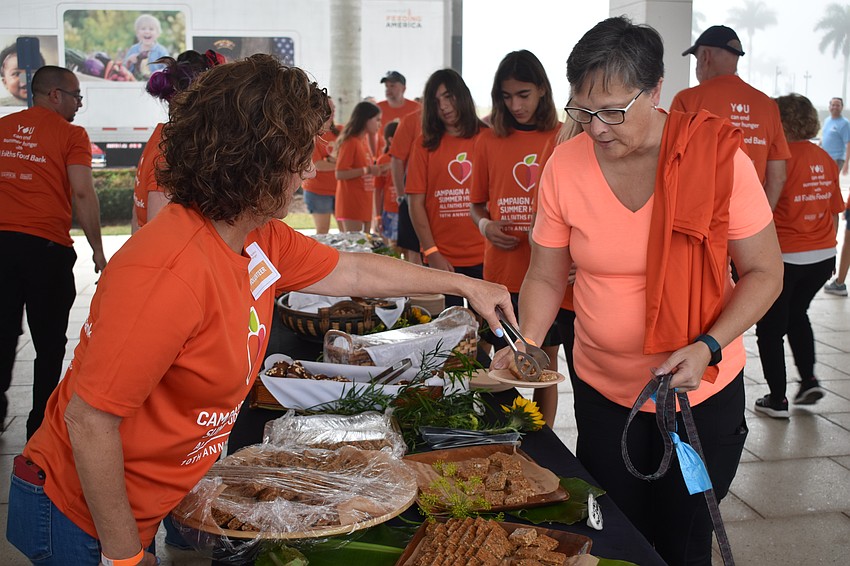 Volunteer Michele Lipman offers food to Rachel Martin
