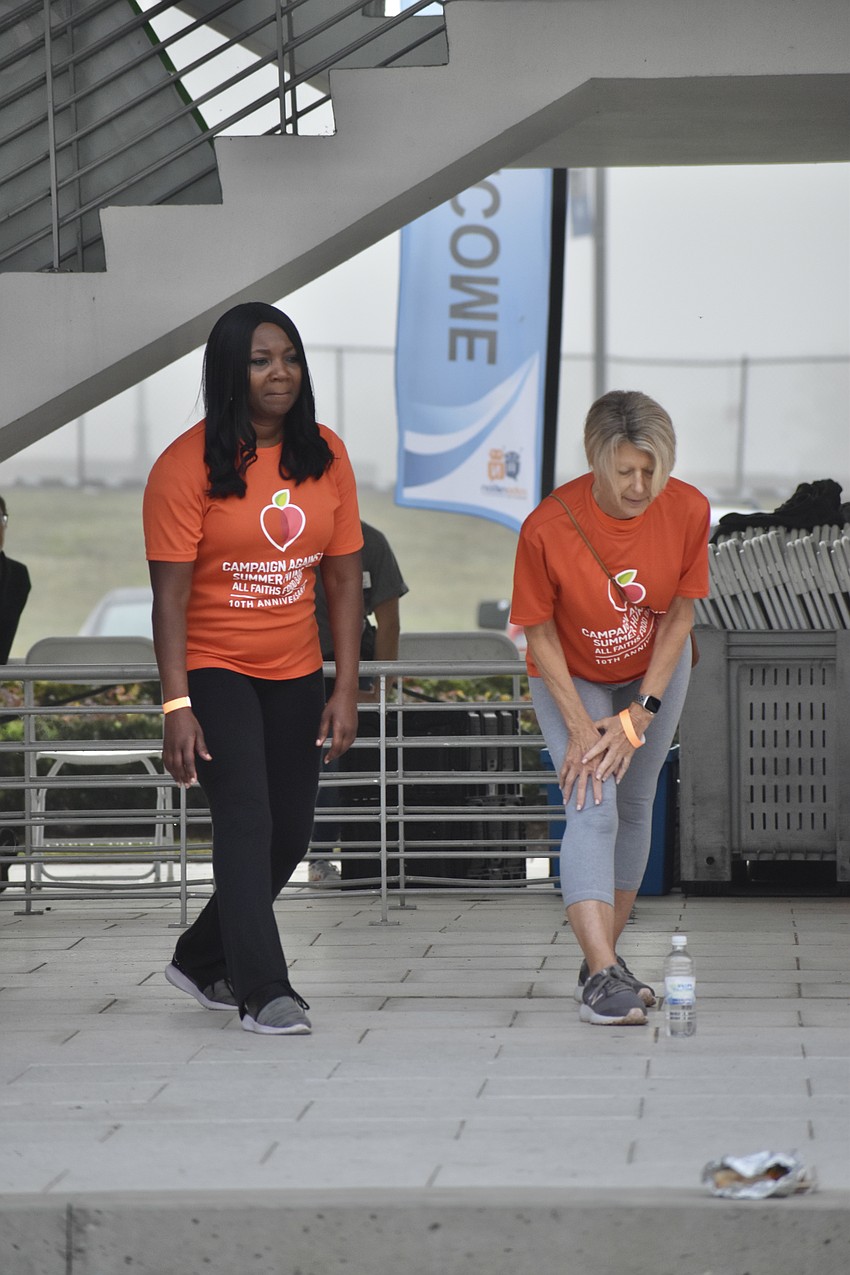 All Faiths Food Bank board members Lashawn Frost and Patricia Courtois participate in a session of stretching led by Eric Hoskins of CORE SRQ.