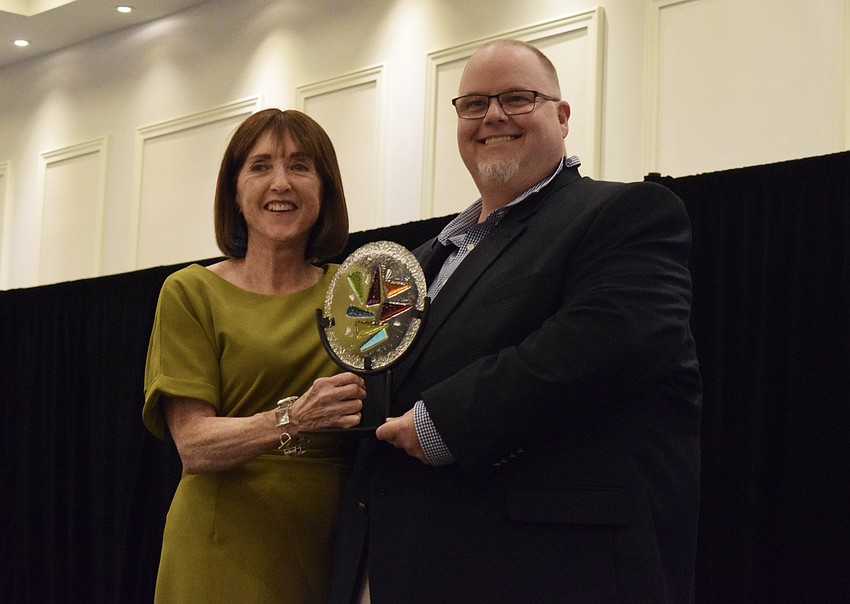 Mary Glass, the treasurer of the Manatee Arts Education Council, presents the Barbara Turner-Grace Visual Arts Education Award to Braden River High School's Bill Ferrell.