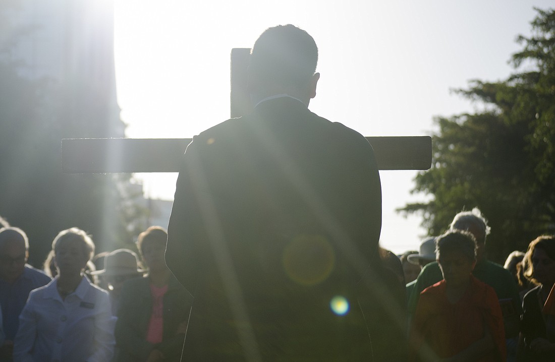 Rev. Chris Wood holds the cross during the Good Friday walk down Main Street.