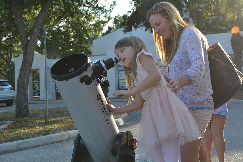 Maya Biter, age 6, takes in a view of the sky through a telescope set up by the Sidewalk Science Center.