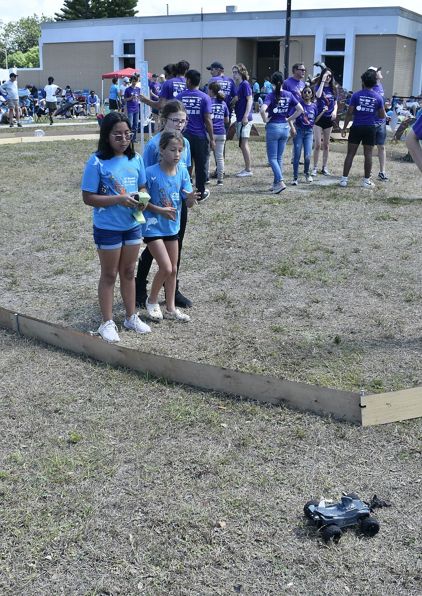 11-year-old Xan Hynes, 11-year-old Adaleena Gordon, and 10-year-old Madelyn Vega of the Daring Dolphins race on the obstacle course track.