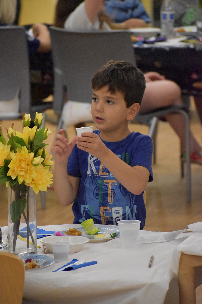 6-year-old Nathaniel Marcus prepares to drink the grape juice, which is blessed as part of the meal.
