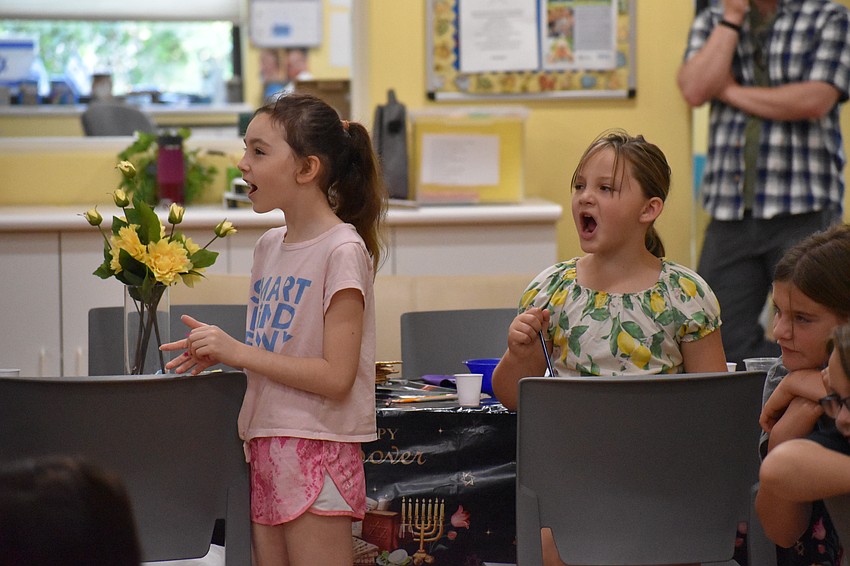 8-year-old Eva Hakim and 8-year-old Elle Zukas chant along to a poem about the Passover story during the Maggid section of the Passover Seder.